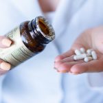 A close-up shot of hands holding a medicine bottle and pills, with a focus on healthcare and medication usage.
